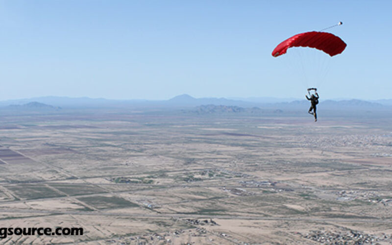Skydiver under a red parachute over Eloy, AZ