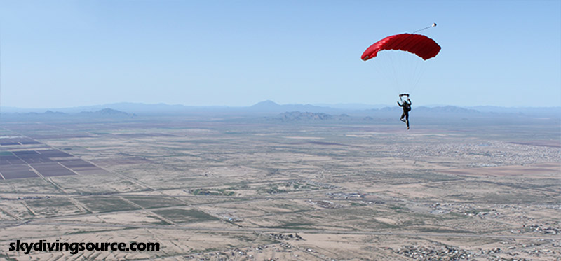 Skydiver under a red parachute over Eloy, AZ