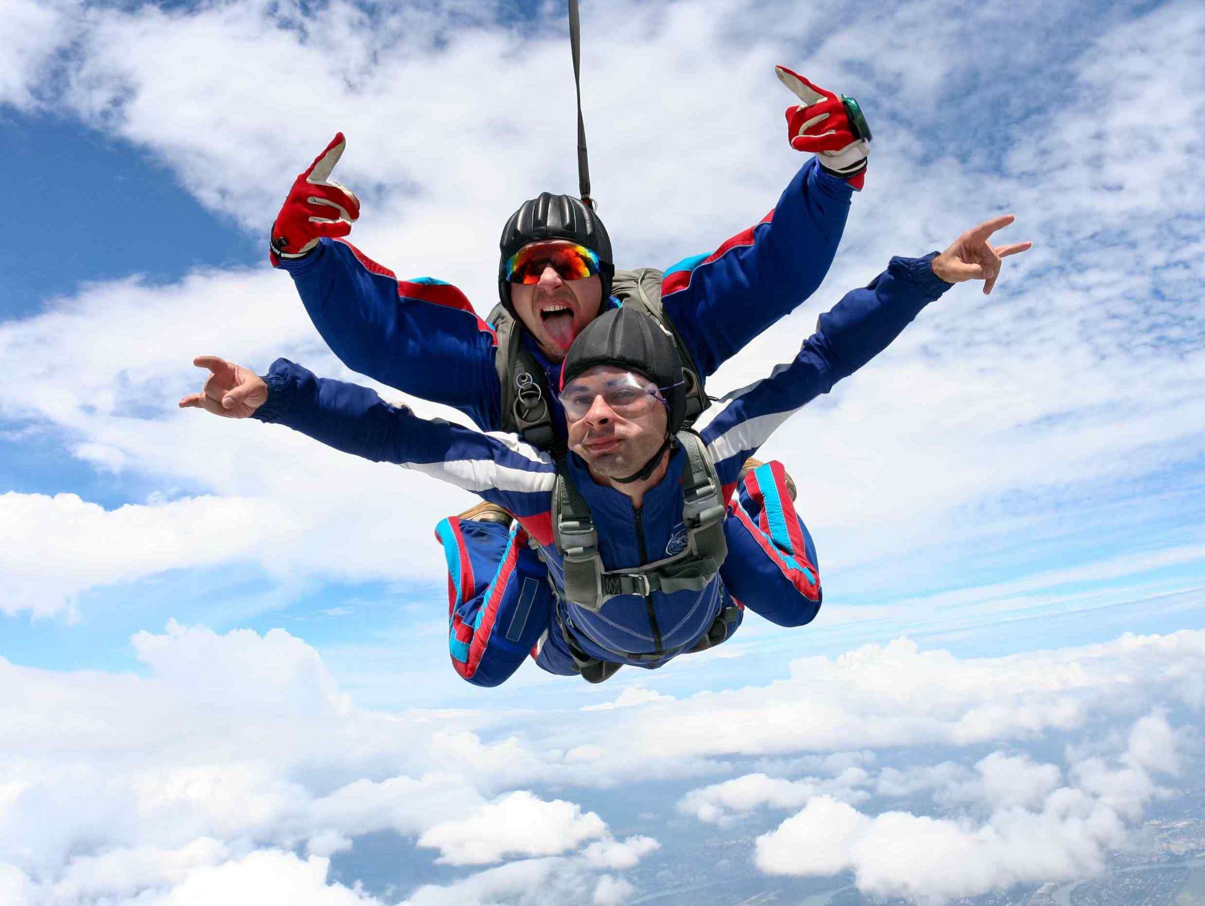 Image of tandem skydive with both people making rock and roll signal with hands