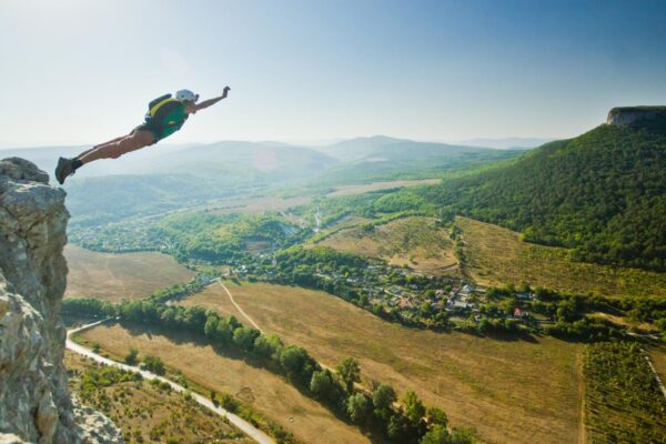 Woman doing a BASE jump from the top of a cliff