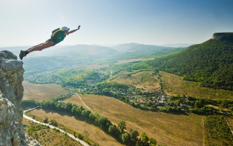 Woman doing a BASE jump from the top of a cliff